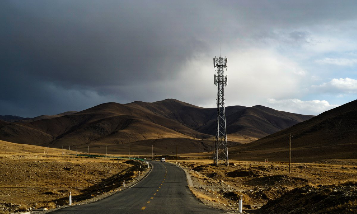 Remote mountain road in Xinjiang with a mobile communication tower