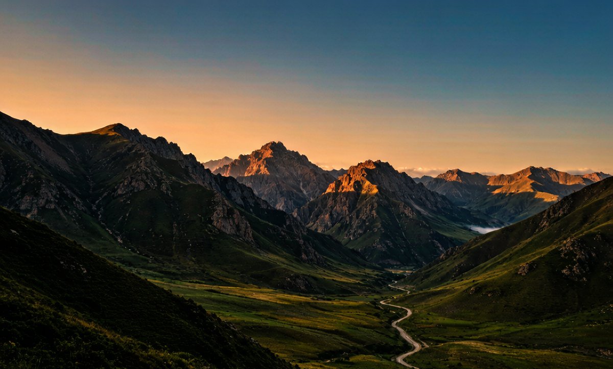 Golden hour light over Tianshan mountains with a winding road
